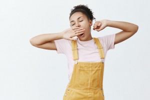 Sleepy dark-skinned woman stretching and yawning