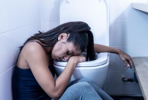 Woman sitting in the bathroom suffering from sickness in early pregnancy