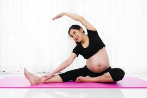 Pregnant woman doing yoga exercise in the living room at home